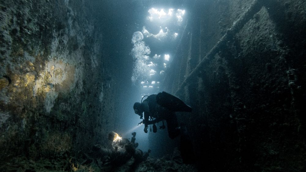 scuba diver inside old wrecked ship