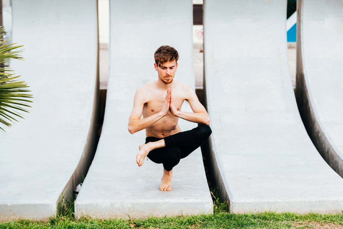 young man doing garudasana during morning in the garden